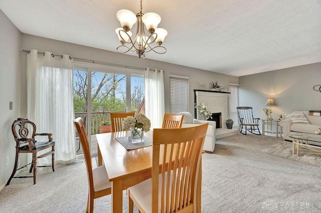 dining area featuring light carpet, a brick fireplace, a textured ceiling, and a notable chandelier