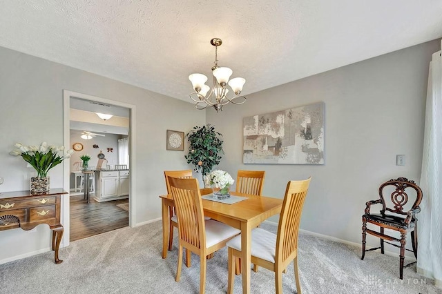 dining room featuring a chandelier, a textured ceiling, carpet flooring, and baseboards