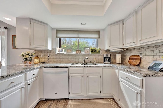 kitchen with white cabinets, tasteful backsplash, dishwasher, and a sink