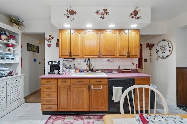 kitchen with light countertops, a sink, light wood-style floors, black dishwasher, and tasteful backsplash