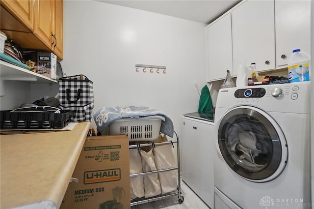 clothes washing area with washer and dryer and cabinet space