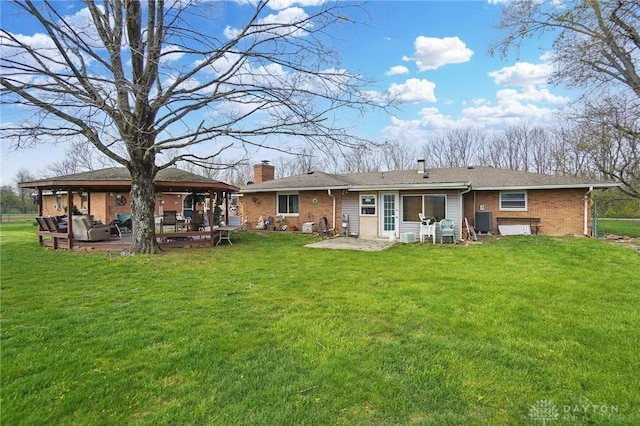 rear view of house with a chimney, brick siding, a patio area, and a gazebo