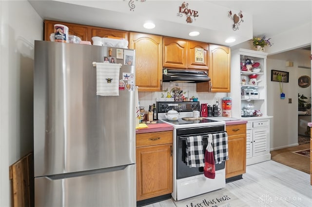 kitchen with white electric range oven, light countertops, backsplash, under cabinet range hood, and freestanding refrigerator