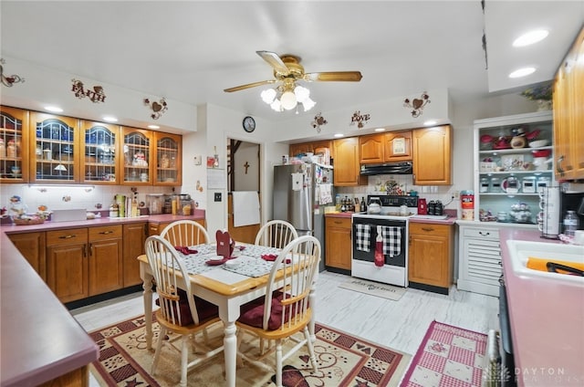 kitchen with white range with electric cooktop, brown cabinetry, under cabinet range hood, and freestanding refrigerator
