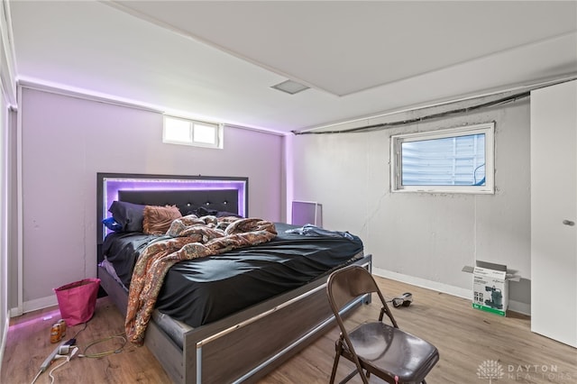 bedroom with wood finished floors, baseboards, and multiple windows