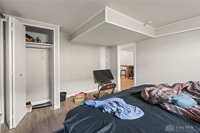 bedroom featuring wood finished floors, a closet, and baseboards