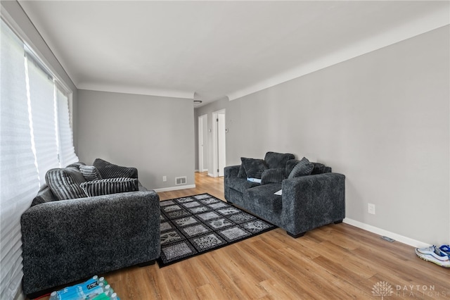 living area featuring wood finished floors, visible vents, and baseboards