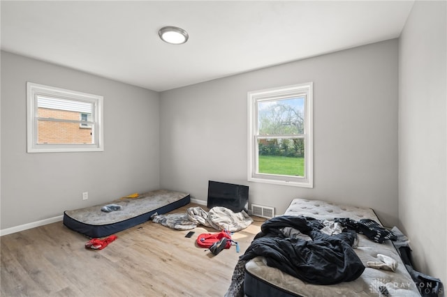 bedroom featuring baseboards, wood finished floors, and visible vents