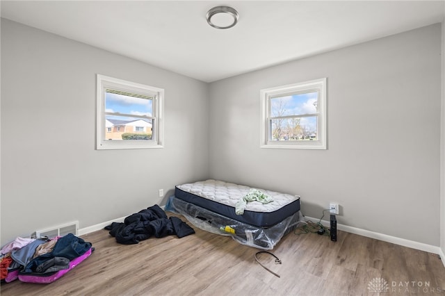 bedroom with baseboards, wood finished floors, and visible vents