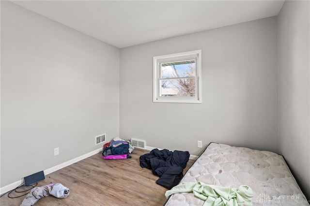 unfurnished bedroom featuring wood finished floors, visible vents, and baseboards