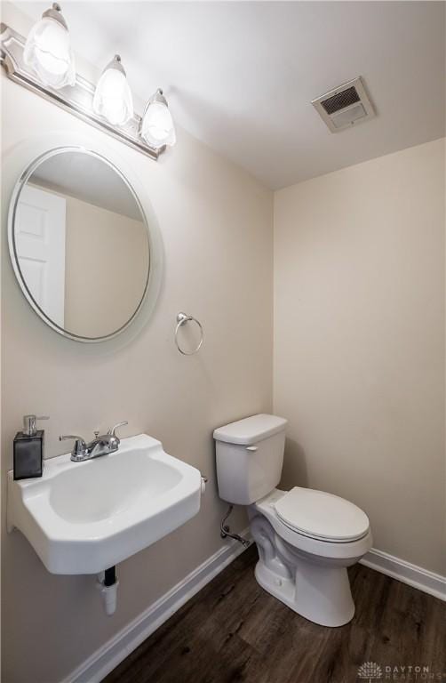 bathroom with wood finished floors, a sink, baseboards, toilet, and visible vents