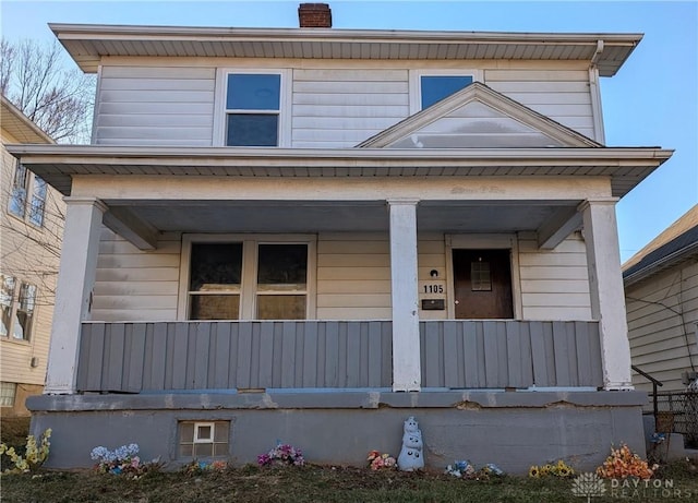view of front of house featuring a chimney and covered porch