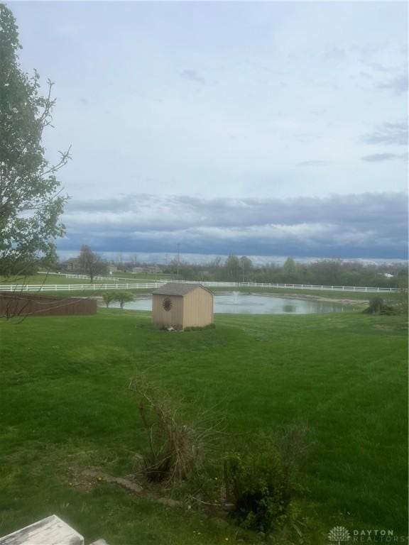 view of yard with an outdoor structure, a shed, and a water view