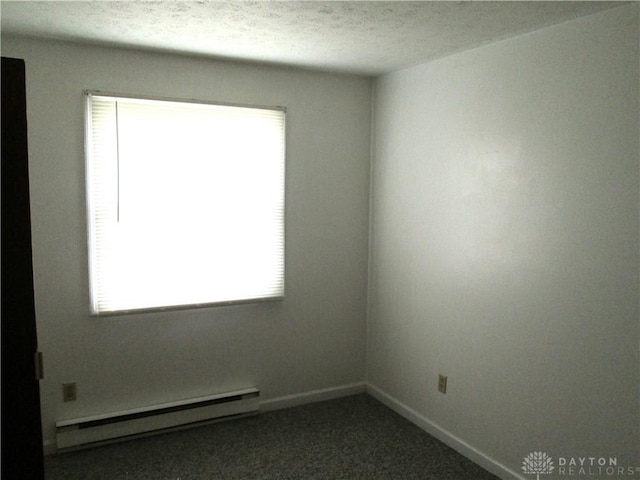 unfurnished room with a baseboard heating unit, a wealth of natural light, carpet floors, and baseboards