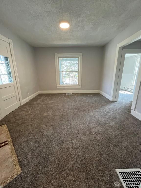 400 S Detroit St, Xenia, OH 45385 - spare room featuring a textured ceiling, baseboards, and dark colored carpet