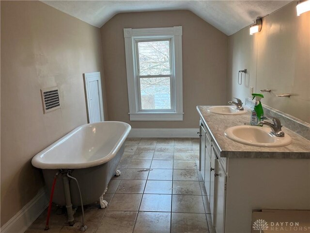 400 S Detroit St, Xenia, OH 45385 - bathroom featuring vaulted ceiling, double vanity, a freestanding tub, and baseboards