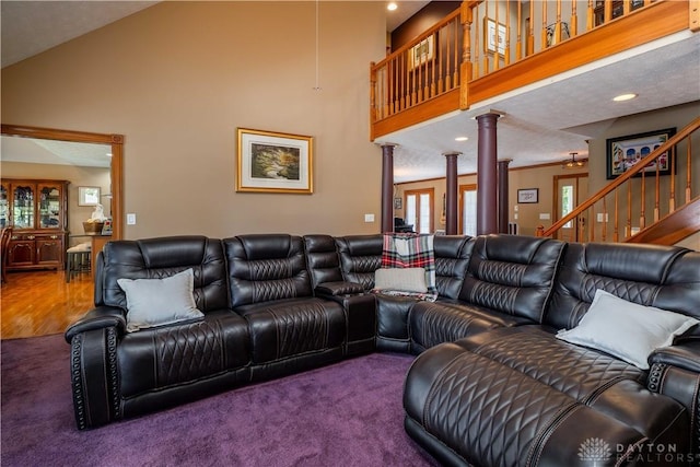 carpeted living area featuring decorative columns, a high ceiling, recessed lighting, and stairway
