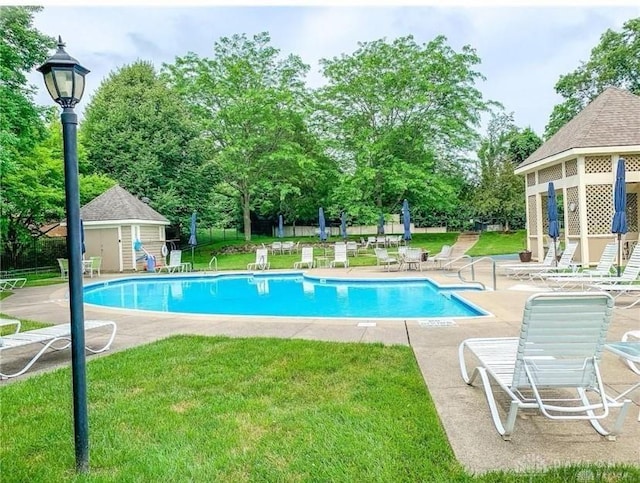 pool featuring an outdoor structure, a yard, and a patio area