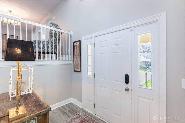 entrance foyer with baseboards, wood finished floors, and stairs