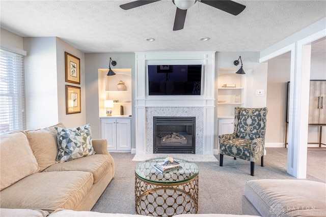 carpeted living area with a fireplace with flush hearth, a textured ceiling, baseboards, built in features, and ceiling fan