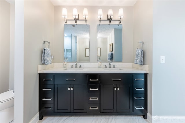 full bath featuring double vanity, marble finish floor, baseboards, and a sink