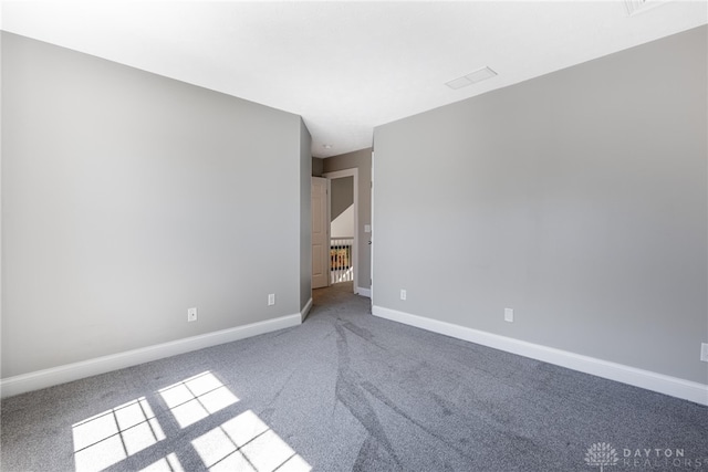 carpeted spare room featuring baseboards and visible vents