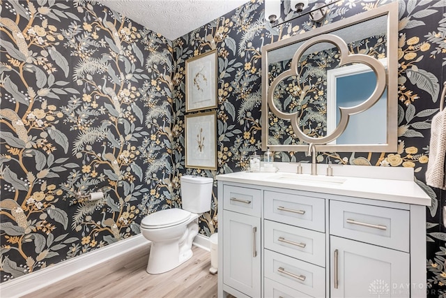 bathroom with wallpapered walls, wood finished floors, toilet, and baseboards