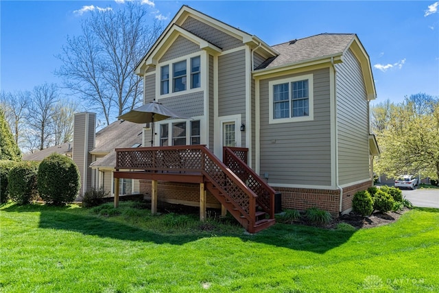 rear view of house featuring stairs, a shingled roof, a yard, a wooden deck, and brick siding
