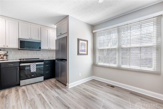 kitchen with light wood finished floors, backsplash, light countertops, baseboards, and appliances with stainless steel finishes