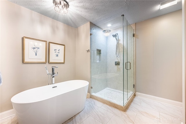 bathroom featuring a shower stall, baseboards, a soaking tub, and a textured ceiling