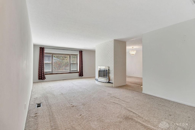 unfurnished living room featuring a chandelier, visible vents, carpet floors, heating unit, and a brick fireplace