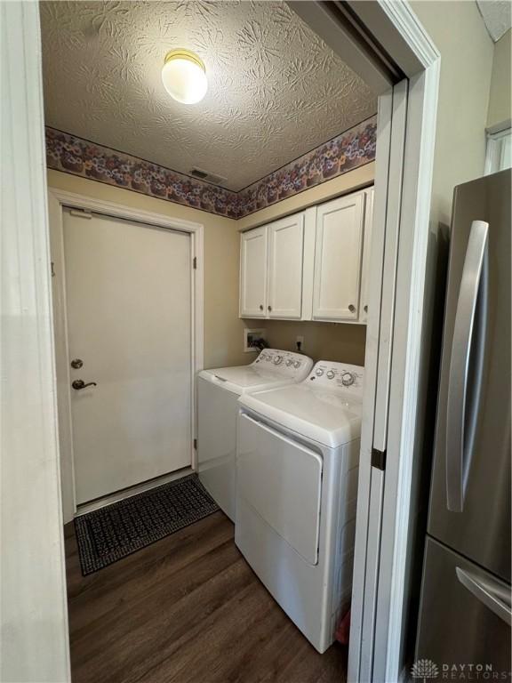 9632 Belfry Ct, Dayton, OH 45458 - laundry room with a textured ceiling, washer and dryer, cabinet space, visible vents, and dark wood-style floors