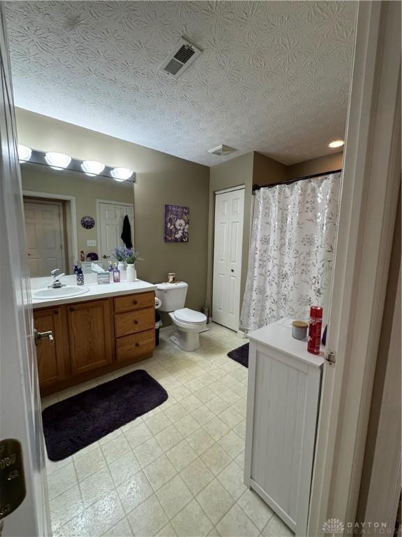 9632 Belfry Ct, Dayton, OH 45458 - bathroom featuring a textured ceiling, vanity, toilet, a shower with shower curtain, and visible vents