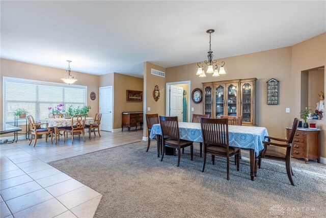 dining area featuring light colored carpet, visible vents, light tile patterned floors, baseboards, and a notable chandelier