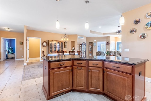 kitchen with ceiling fan, a center island, hanging light fixtures, brown cabinets, and light tile patterned floors