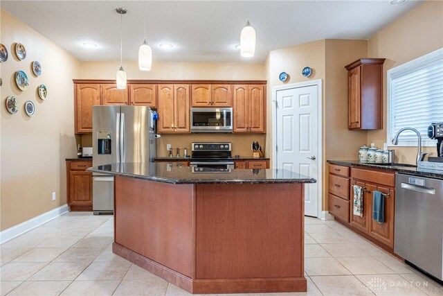 kitchen with light tile patterned flooring, baseboards, a center island, a sink, and stainless steel appliances