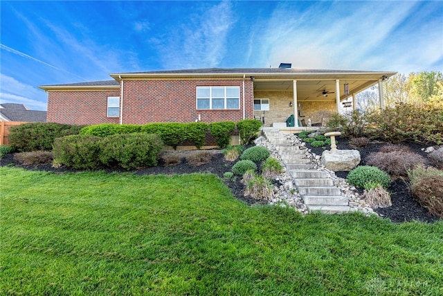 view of front of property featuring stairway, ceiling fan, brick siding, and a front yard