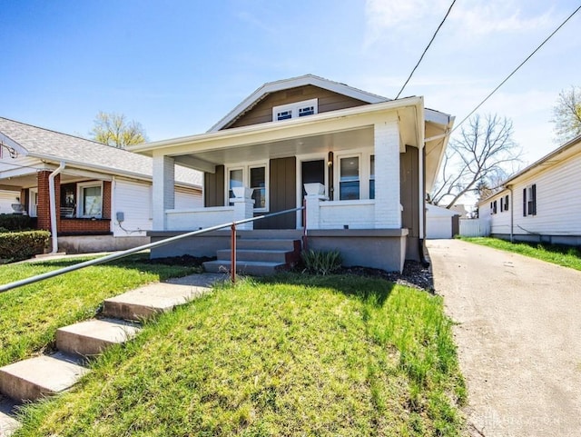 bungalow with a porch, a front lawn, board and batten siding, and a detached garage