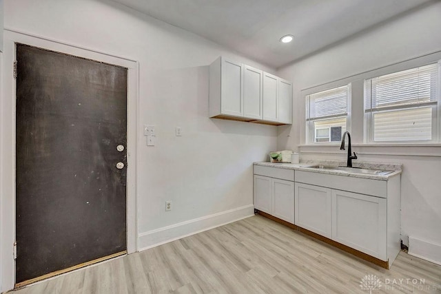 clothes washing area featuring recessed lighting, baseboards, a sink, and light wood-type flooring