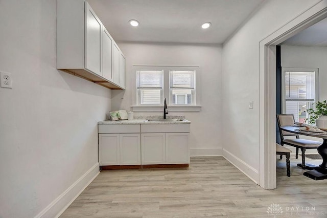 interior space featuring baseboards, a healthy amount of sunlight, a sink, and light wood-style floors
