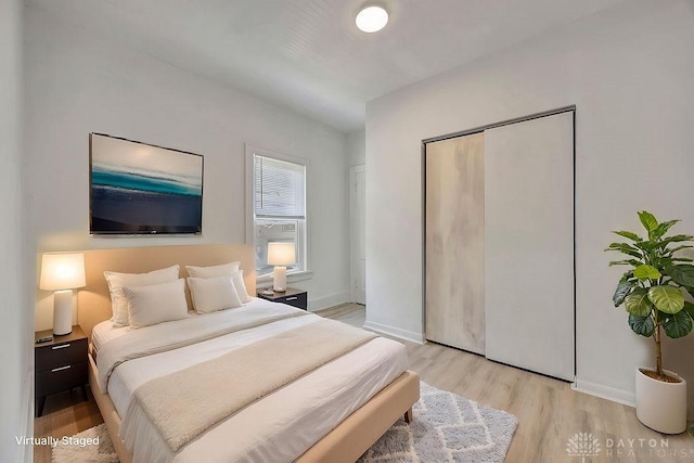 bedroom with light wood finished floors, baseboards, and a closet