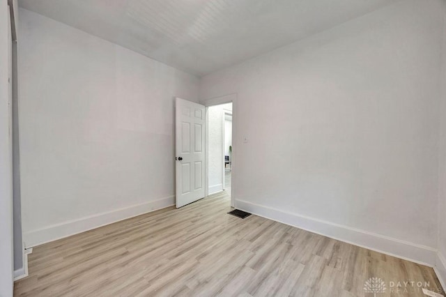 spare room with baseboards, visible vents, and light wood finished floors