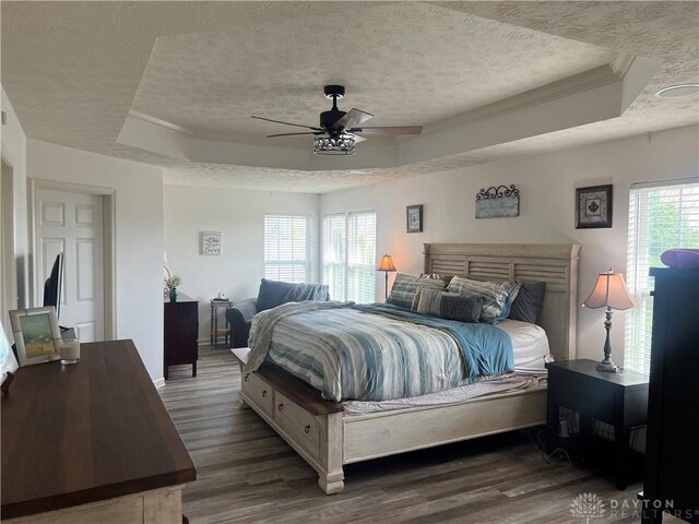 3513 Black Squirrel Way, Springboro, OH 45005 - bedroom with a raised ceiling, a textured ceiling, wood finished floors, multiple windows, and crown molding