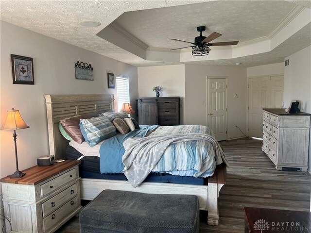3513 Black Squirrel Way, Springboro, OH 45005 - bedroom with a raised ceiling, dark wood-style flooring, a textured ceiling, crown molding, and baseboards