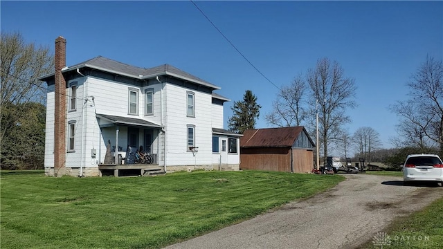 view of side of property with a chimney and a lawn