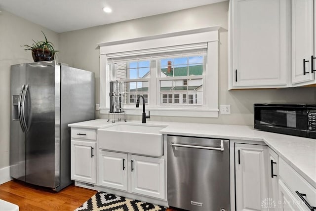 203 W Plum St, Saint Paris, OH 43072 - kitchen featuring stainless steel appliances, wood finished floors, white cabinetry, a sink, and light countertops