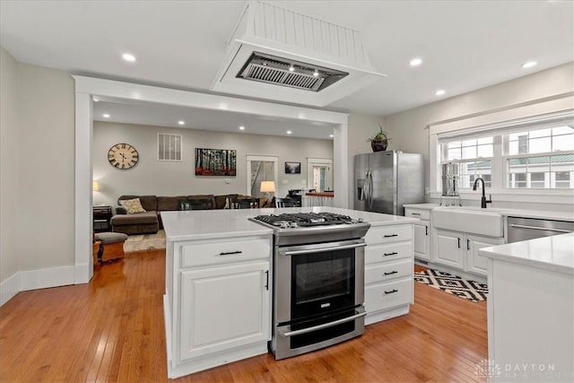 203 W Plum St, Saint Paris, OH 43072 - kitchen with appliances with stainless steel finishes, a sink, open floor plan, a kitchen island, and light wood-type flooring