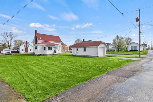 203 W Plum St, Saint Paris, OH 43072 - view of side of home featuring driveway, an outbuilding, a yard, a detached garage, and a residential view