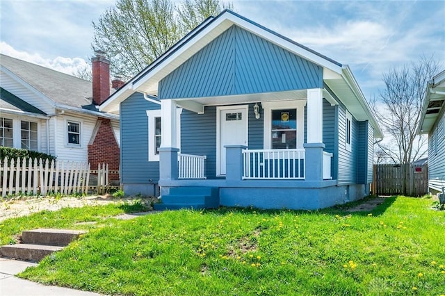bungalow-style home with fence, a front lawn, and covered porch