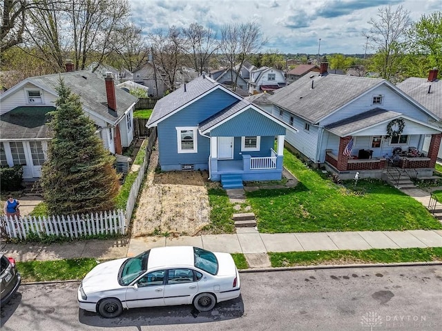 bungalow-style house featuring a front lawn, fence, a residential view, and covered porch